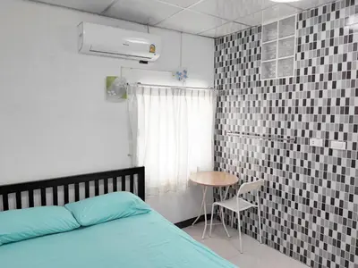 a bedroom with a bed and a table and a window at Mansion 24 in Bangkok