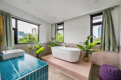 a bathroom with a tub and a sink and windows at MIQ Ekkamai1 - 5BR house 65 inch TV in Bangkok
