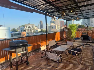 a patio with a grill and tables and chairs on a building at 4 Bedroom House with Beautiful Rooftop near BTS Ekkamai in Bangkok