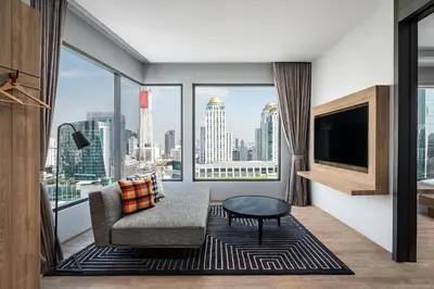 a living room with a couch and a large window at Moxy Bangkok Ratchaprasong by Marriott in Bangkok