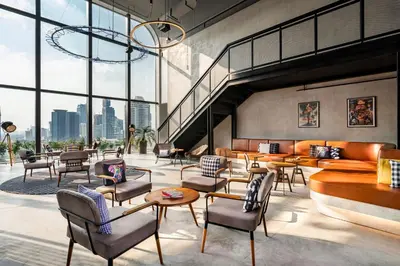 a lobby with chairs and tables and a large window at Moxy Bangkok Ratchaprasong by Marriott in Bangkok