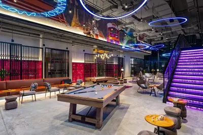 a ping pong table in a room with tables and chairs at Moxy Bangkok Ratchaprasong by Marriott in Bangkok