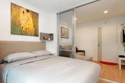 a bedroom with a bed and a painting on the wall at Fully Furnished Studio Apartments in Bangkok