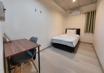 a room with a bed and a desk and a table at Chaiwat Hostel in Bangkok