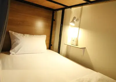 a bed with a white pillow and a light on it at Chaiwat Hostel in Bangkok
