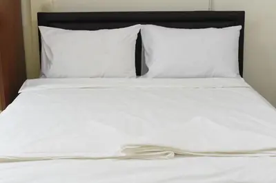 a white bed with white sheets and pillows at Chaiwat Hostel in Bangkok