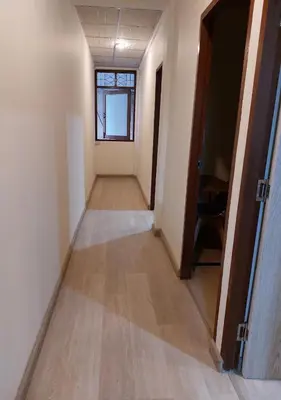 a hallway of an empty room with a window and a door at Chaiwat Hostel in Bangkok