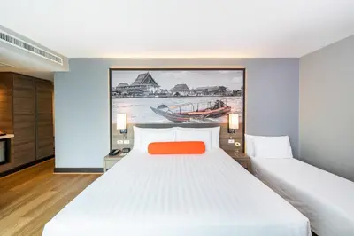 a bedroom with two beds and a painting on the wall at Citrus Sukhumvit 11 by Compass Hospitality in Bangkok