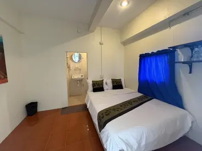 a bedroom with a large white bed with blue curtains at Greenhouse Bangkok Khaosan in Bangkok