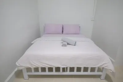 a bed with white sheets and purple pillows at Bangkok Cozy Home @Khaosan Road in Bangkok