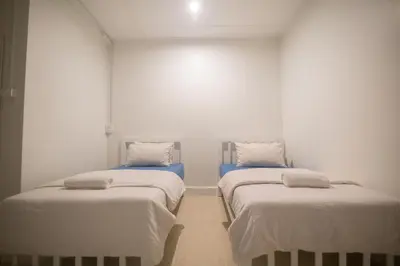 two beds in a room with white walls at Bangkok Cozy Home @Khaosan Road in Bangkok