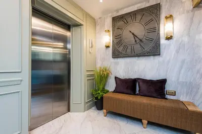 a large clock on a wall next to a couch at The Elite @ Thong Lor 25 in Bangkok