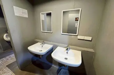 a bathroom with two sinks and two mirrors at Sukhum Huai Khwang Guest House in Bangkok