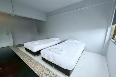 two beds in a small room with white walls at Sukhum Huai Khwang Guest House in Bangkok