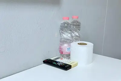 a remote control and a bottle of water and a roll of toilet paper at Sukhum Huai Khwang Guest House in Bangkok