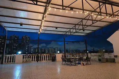 a patio with chairs and a table with a view of a city at Sukhum Huai Khwang Guest House in Bangkok