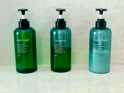 three bottles of shampoo and conditioner sitting on a counter at The Apartium - Modern Apartment Rentals in Bangkok
