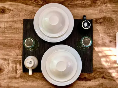 two white plates on a wooden table with glasses at The Apartium - Modern Apartment Rentals in Bangkok