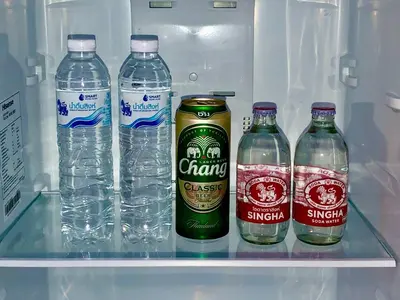 a refrigerator filled with bottles of water and soda at The Apartium - Modern Apartment Rentals in Bangkok