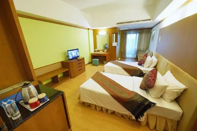 a hotel room with two beds and a television at Riverside Bangkok Hotel in Bangkok