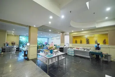 a lobby of a hotel with a woman sitting at a table at Riverside Bangkok Hotel in Bangkok