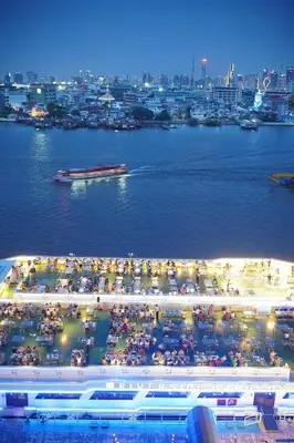 a large crowd of people on a beach near the water at Riverside Bangkok Hotel in Bangkok