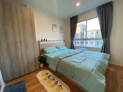 a bedroom with a large bed and a window at Garden Oasis Apartment: Condo Near Bangkok River in Ban Sai Ma
