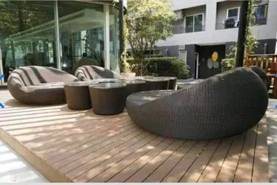 a wooden deck with chairs and tables and a building at Elio Sukhumvit 64: Chic Space in Bangkok