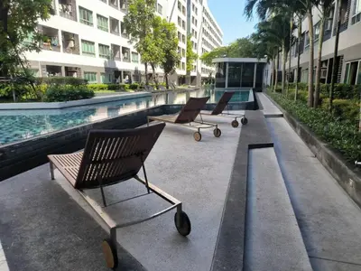 a row of chairs sitting next to a swimming pool at Elio Sukhumvit 64: Chic Space in Bangkok