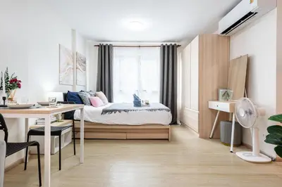 a bedroom with a bed and a desk and a window at Elio Del Ray BTS Punnawithi in Bangkok