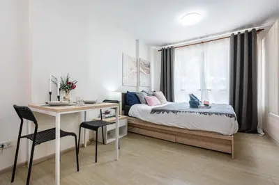 a bedroom with a bed and a desk and a window at Elio Del Ray BTS Punnawithi in Bangkok