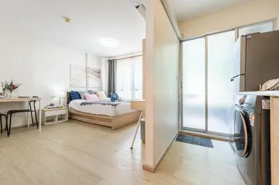 a small apartment with a bed and a room with a refrigerator at Elio Del Ray BTS Punnawithi in Bangkok