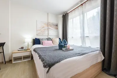 a bedroom with a large bed with a window at Elio Del Ray BTS Punnawithi in Bangkok