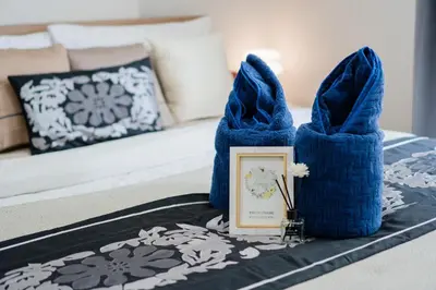 a pair of blue towels on a table with a picture at Elio Sukhumvit 64 in Bangkok