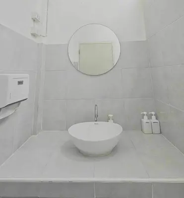 a white bathroom with a sink and a mirror at W District Guesthouse in Bangkok