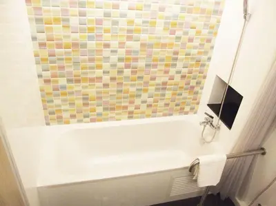 a bathroom with a white tub and a colorful shower curtain at Grand Tower Inn Sathorn Hotel in Bangkok