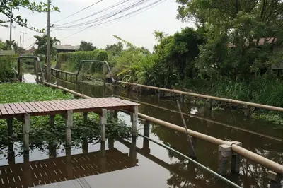 a wooden bridge over a body of water at Thaihome Resort in Ban Bang Muang