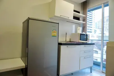 a kitchen with a refrigerator and a microwave at Hip & Funky Sathon15 apartment close to BTS St Louis in Bangkok