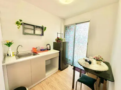 a kitchen with a sink and a table and a refrigerator at เช่ารายเดือน DCon Rattanathibet in Ban Sai Ma