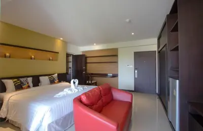 a bedroom with a bed and a red couch at Chateau de Sukhumvit in Bangkok