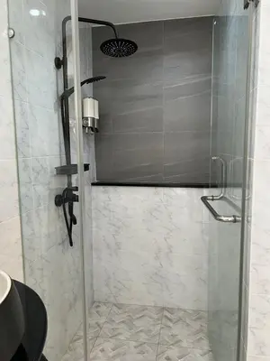 a shower with a glass door in a bathroom at Quinstel Guesthouse in Bangkok