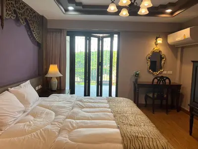 a large white bed in a bedroom with a window at Quinstel Guesthouse in Bangkok