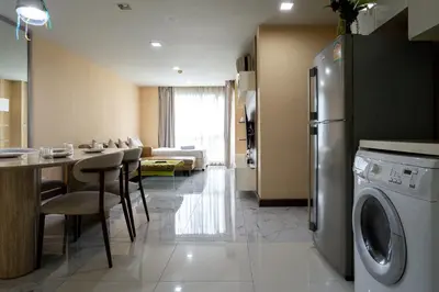 a kitchen and living room with a table and a refrigerator at LIV@5 Condominium in Makkasan