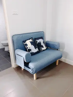 a blue couch with pillows on it in a room at Mitr Inn Mrt Samyot Station - The Grand Palace in Bangkok