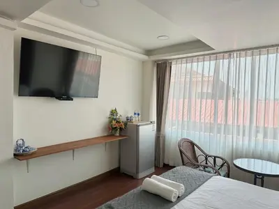 a room with a television on the wall and a table at Longzhu Guesthouse in Bangkok