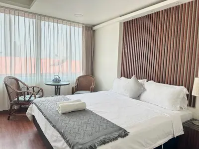 a bedroom with a large white bed and a table at Longzhu Guesthouse in Bangkok