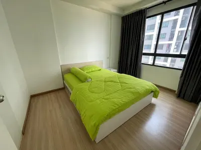 a bedroom with a bed with a green comforter and a window at 2BR Apartment in Bangkok