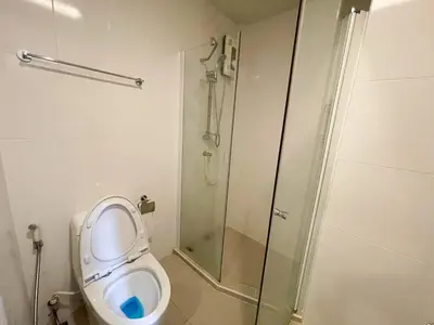 a bathroom with a toilet and a glass shower at 2BR Apartment in Bangkok