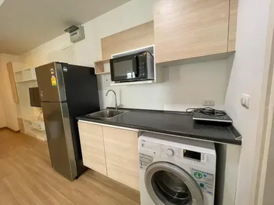 a small kitchen with a washing machine and a microwave at 2BR Apartment in Bangkok