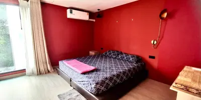 a red bedroom with a bed with a pink pillow on it at Hip and funky apartment silom Soi 3, with rooftop view in Bangkok